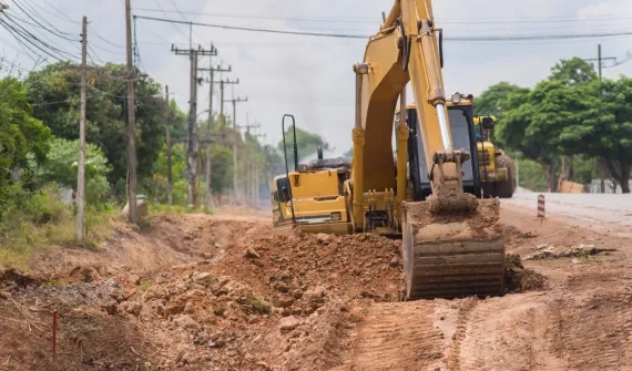 An excavator digging on the side of the road