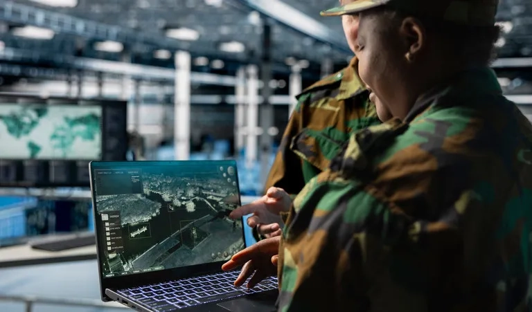 Personnel reviewing aerial imagery and geospatial intelligence data on a laptop